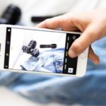 Smartphone fotografiert Jeans und Kamera