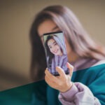 Junge Frau mit braunen Haaren macht Selfie