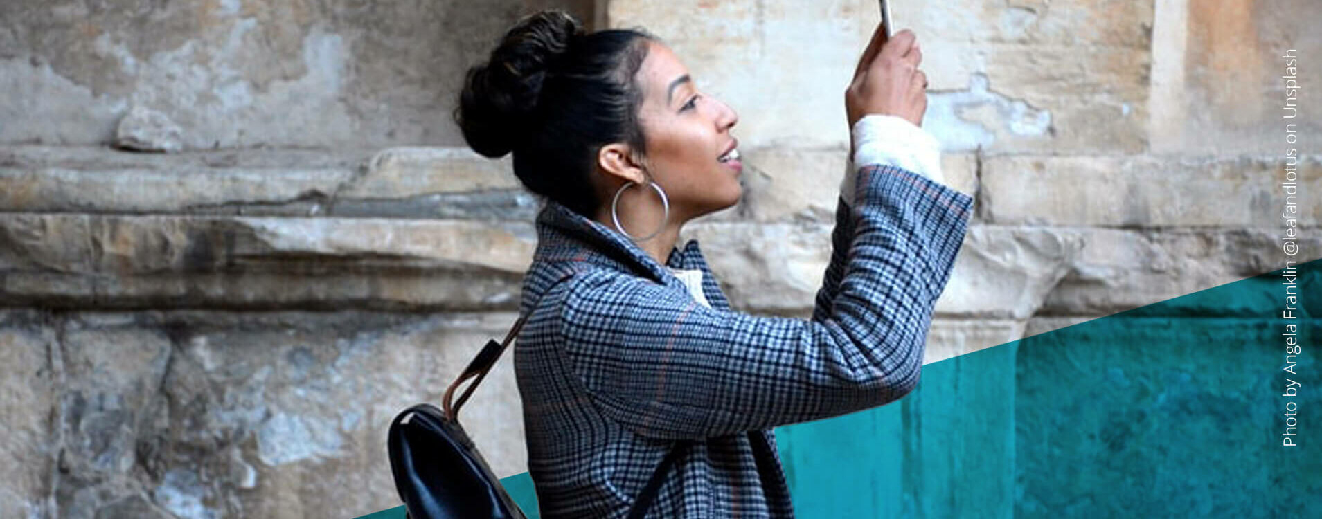 Junge Frau hält ihr Handy nach oben und schaut interessiert darauf