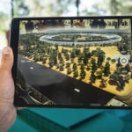 Hand hält ein Tablet, auf dem mit Augmented Reality eine Landschaft abgebildet ist